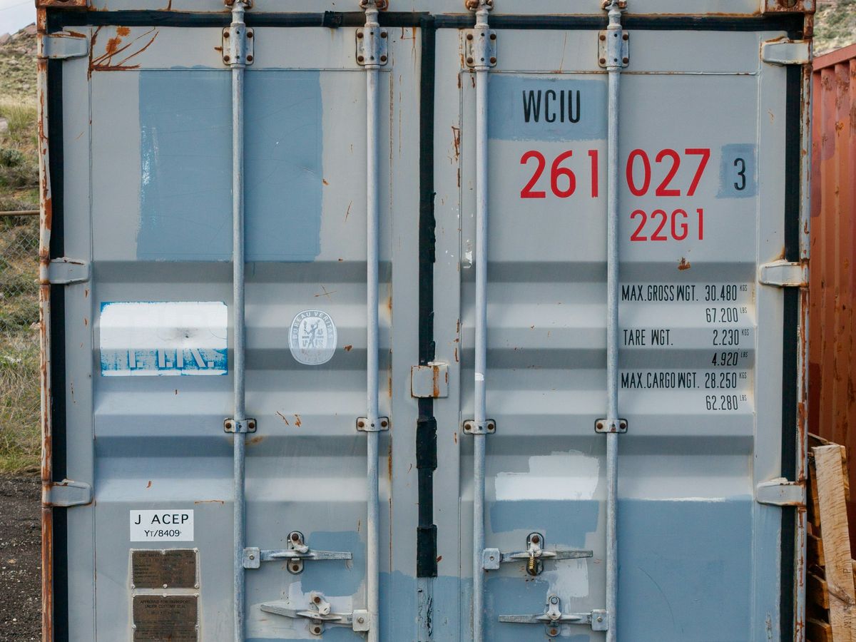 Weathered blue shipping container doors with dents and rust